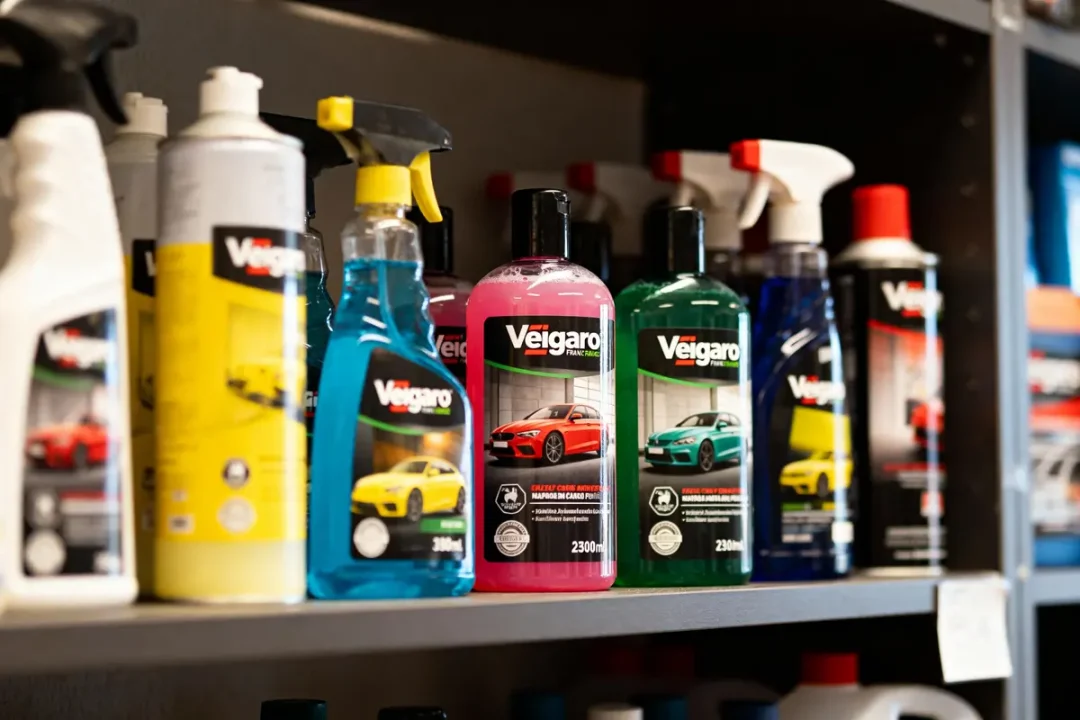 Étagère avec divers produits de nettoyage pour voitures en bouteilles colorées, étiquetées "Veigaro".
