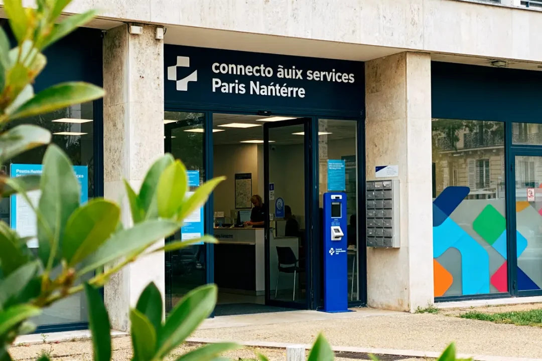 Entrée d'un centre "connecto aux services" à Paris Nanterre, avec distributeur bleu et plantes devant.